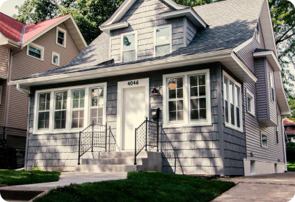 A photograph of the exterior of a newly remodeled Minneapolis home shot from the street with the sun breaking through the trees on a warm Minnesota morning.